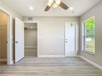 an empty room with wooden floor cabinet and windows