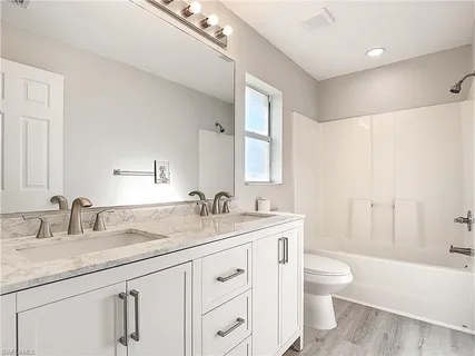 a bathroom with a granite countertop sink a toilet and a bathtub