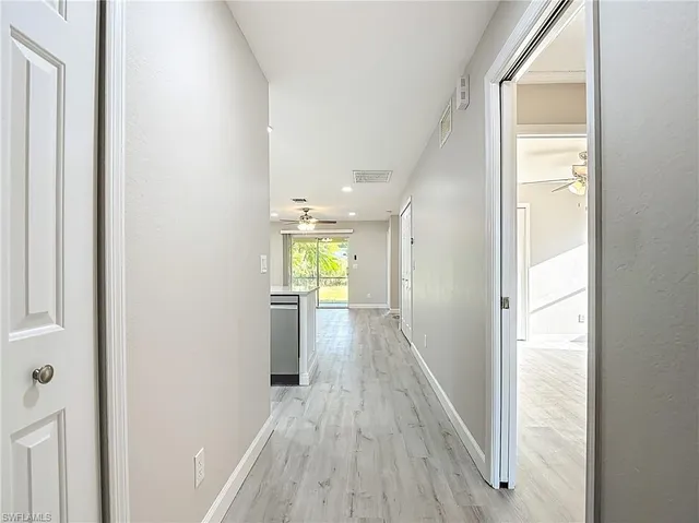 a view of a hallway with wooden floor and a bathroom