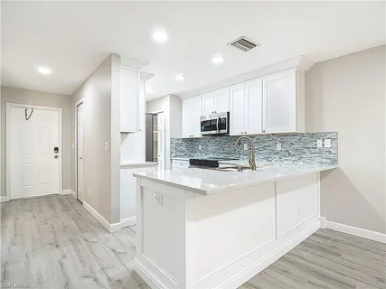 a view of kitchen with stainless steel appliances granite countertop a stove and a sink