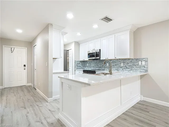 a view of kitchen with stainless steel appliances granite countertop a stove and a sink