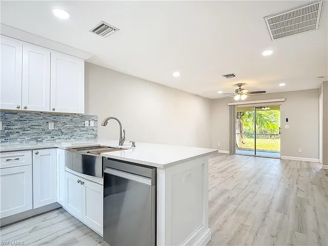a kitchen with a sink dishwasher a stove and white cabinets with wooden floor