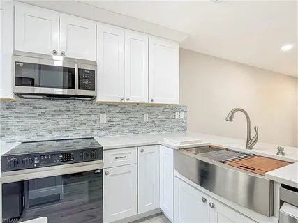 a kitchen with stainless steel appliances granite countertop grey cabinets a stove a sink and dishwasher