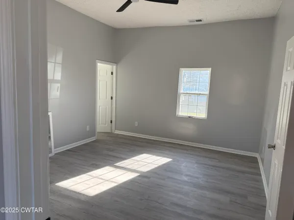 an empty room with wooden floor cabinet and windows