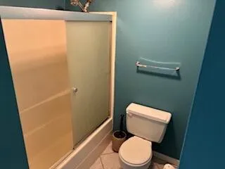 a white toilet sitting next to a shower