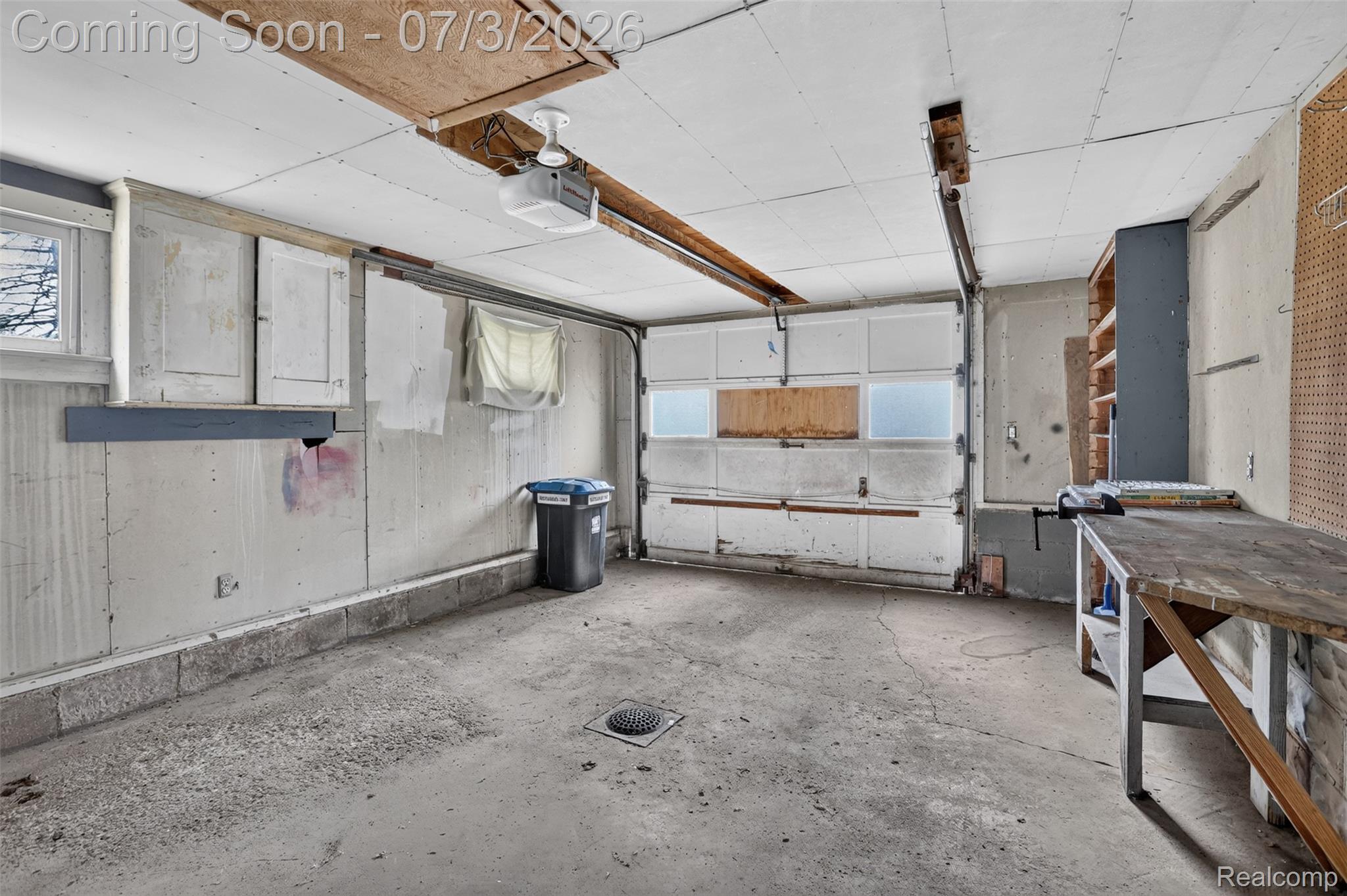 4322 Baker Road Bridgeport, MI 48722 - Photo 24 of 29 Single-bay garage featuring a concrete floor, built-in shelving, a workbench, and an overhead garage door