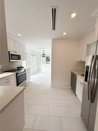 a kitchen with granite countertop a refrigerator and a stove top oven