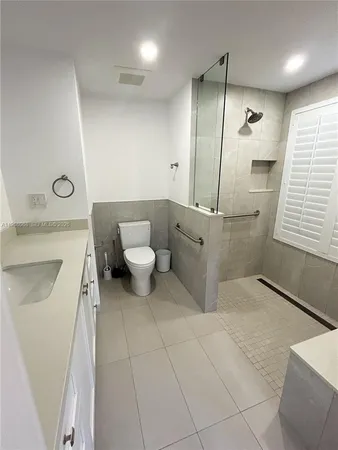 a view of a hallway with wooden floor and a bathroom