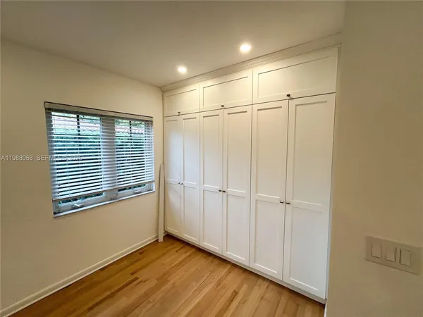 a view of an empty room with wooden floor and a ceiling fan