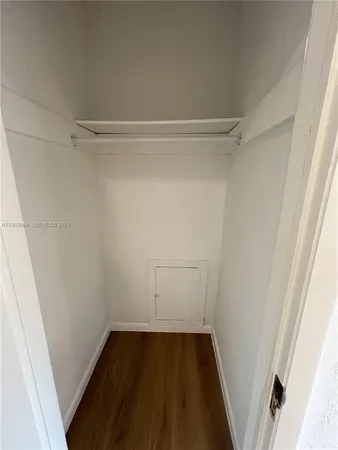a view of a hallway with wooden floor and a bathroom
