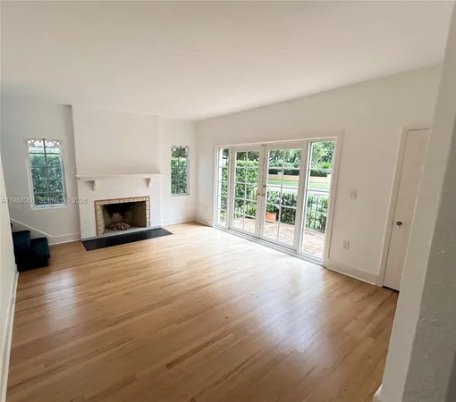 an empty room with wooden floor fireplace and windows