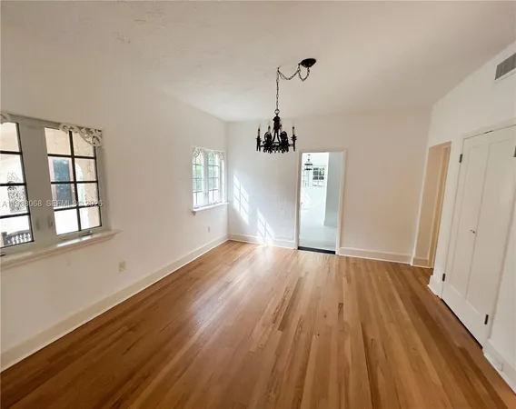 a view of empty room with wooden floor and window