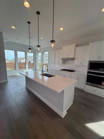 a large kitchen with kitchen island a large counter top a stove a sink and a wooden floors