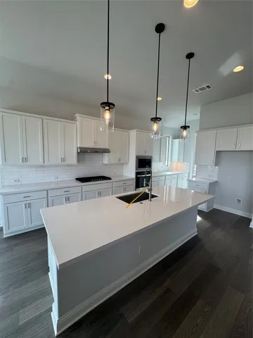 a large kitchen with kitchen island a stove a sink a center island and wooden floor