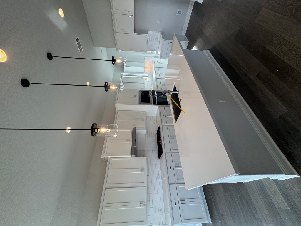 232 Camille Street Leander, TX 78641 - Photo 4 of 26 a large kitchen with kitchen island a stove a sink a center island and wooden floor