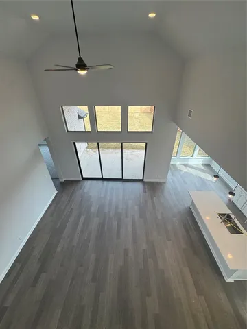 an empty room with windows and ceiling fan