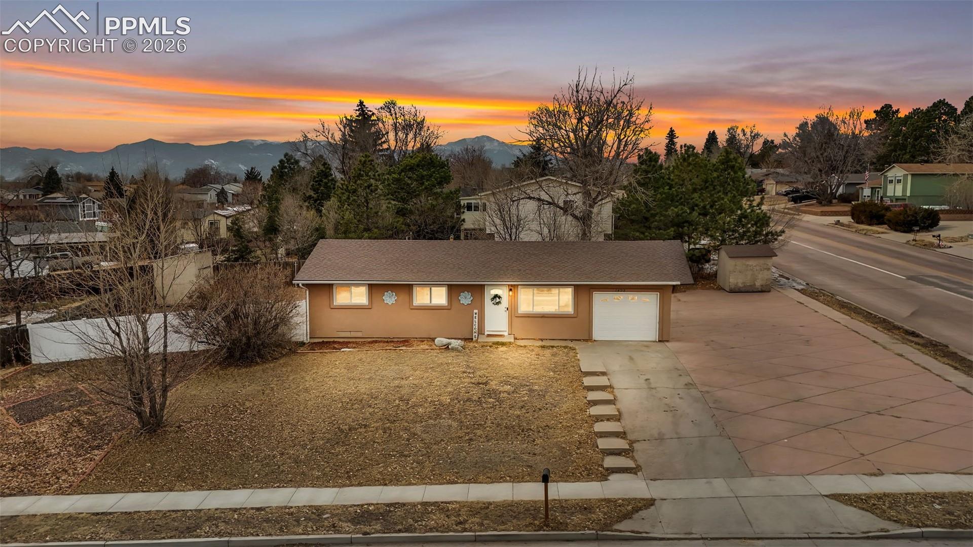 1498 Peterson Road Colorado Springs, CO 80915 - Photo 2 of 44 Single story home featuring concrete driveway, a garage, stucco siding, roof with shingles, and a mountain view