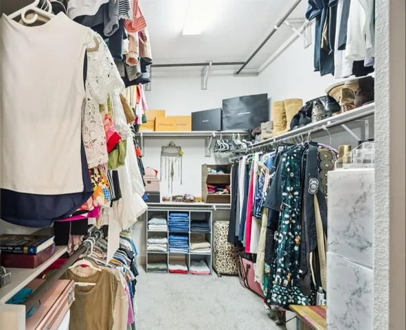 a view of walk in closet with clothes and shoes