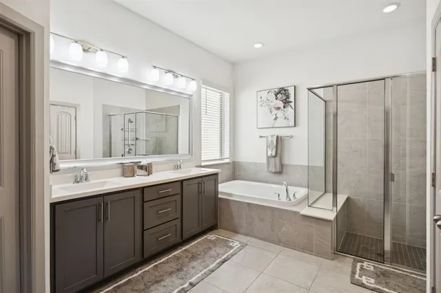 a bathroom with a double vanity sink a mirror a bathtub and shower
