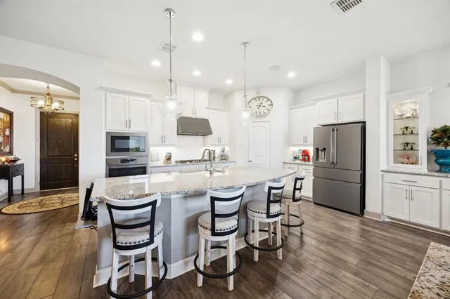 a large kitchen with kitchen island a counter space a sink and stainless steel appliances
