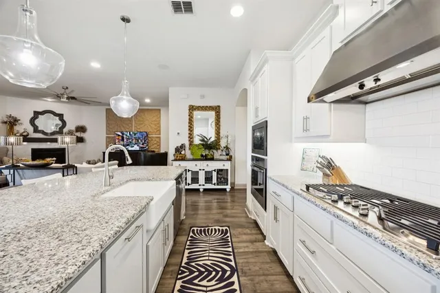 a large kitchen with stainless steel appliances kitchen island granite countertop a lot of counter space and wooden floor