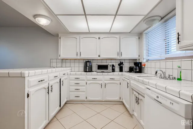 a kitchen with white cabinets appliances and a sink