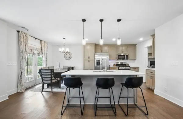 a kitchen with stainless steel appliances a dining table chairs and wooden floor