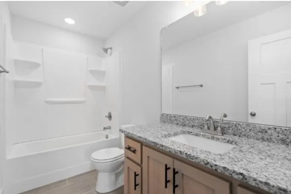 a bathroom with a granite countertop sink a toilet and shower
