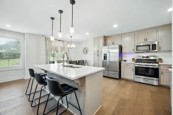 a kitchen with stainless steel appliances a stove a sink a microwave a refrigerator and chairs