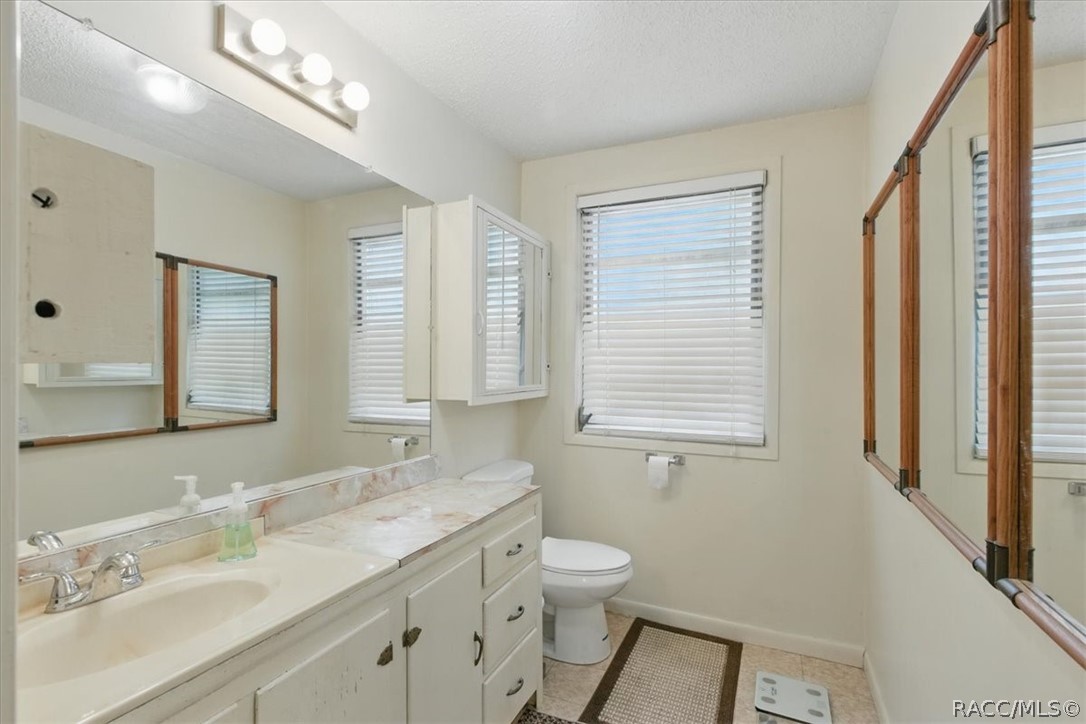 6 62nd Street Yankeetown, FL 34498 - Photo 11 of 55 a bathroom with a granite countertop sink a large mirror a toilet and a shower