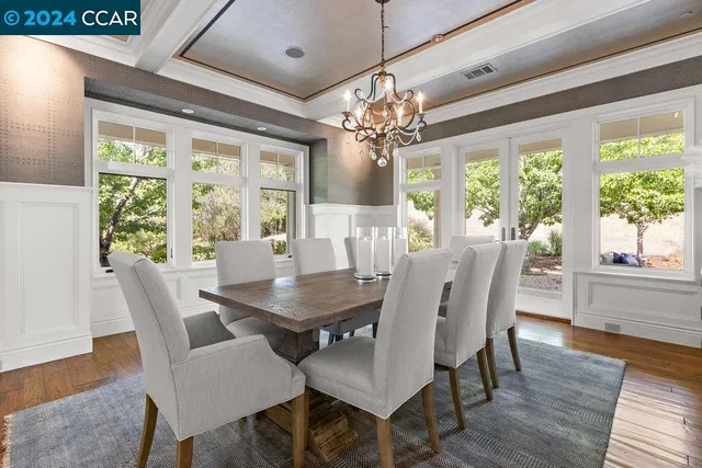 a dining room with wooden floor a chandelier a wooden table and chairs