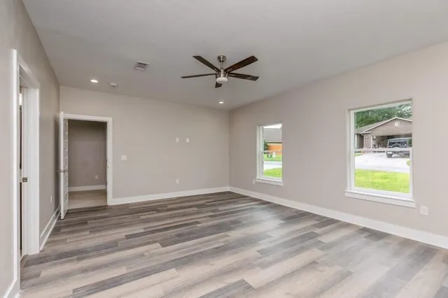 an empty room with windows and fan