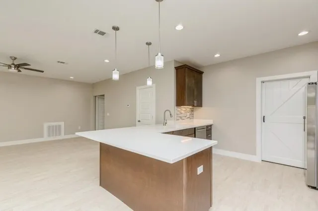 a view of a kitchen island a sink and a refrigerator