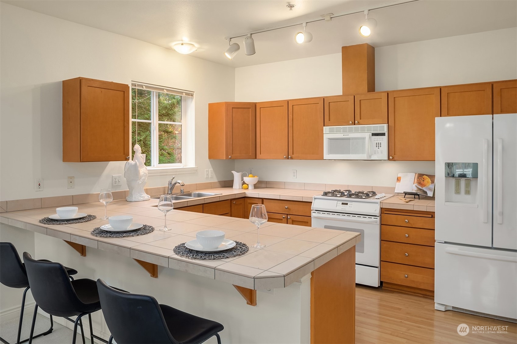 17432 Bothell Way Northeast, Unit B206 Bothell, WA 98011 - Photo 11 of 28 a kitchen with a sink a stove a refrigerator and white cabinets with wooden floor