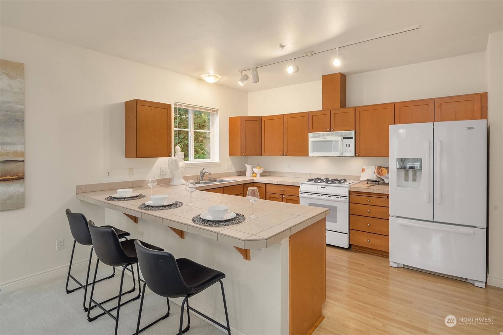 17432 Bothell Way Northeast, Unit B206 Bothell, WA 98011 - Photo 12 of 28 a kitchen with a refrigerator a stove a sink and white cabinets with wooden floor