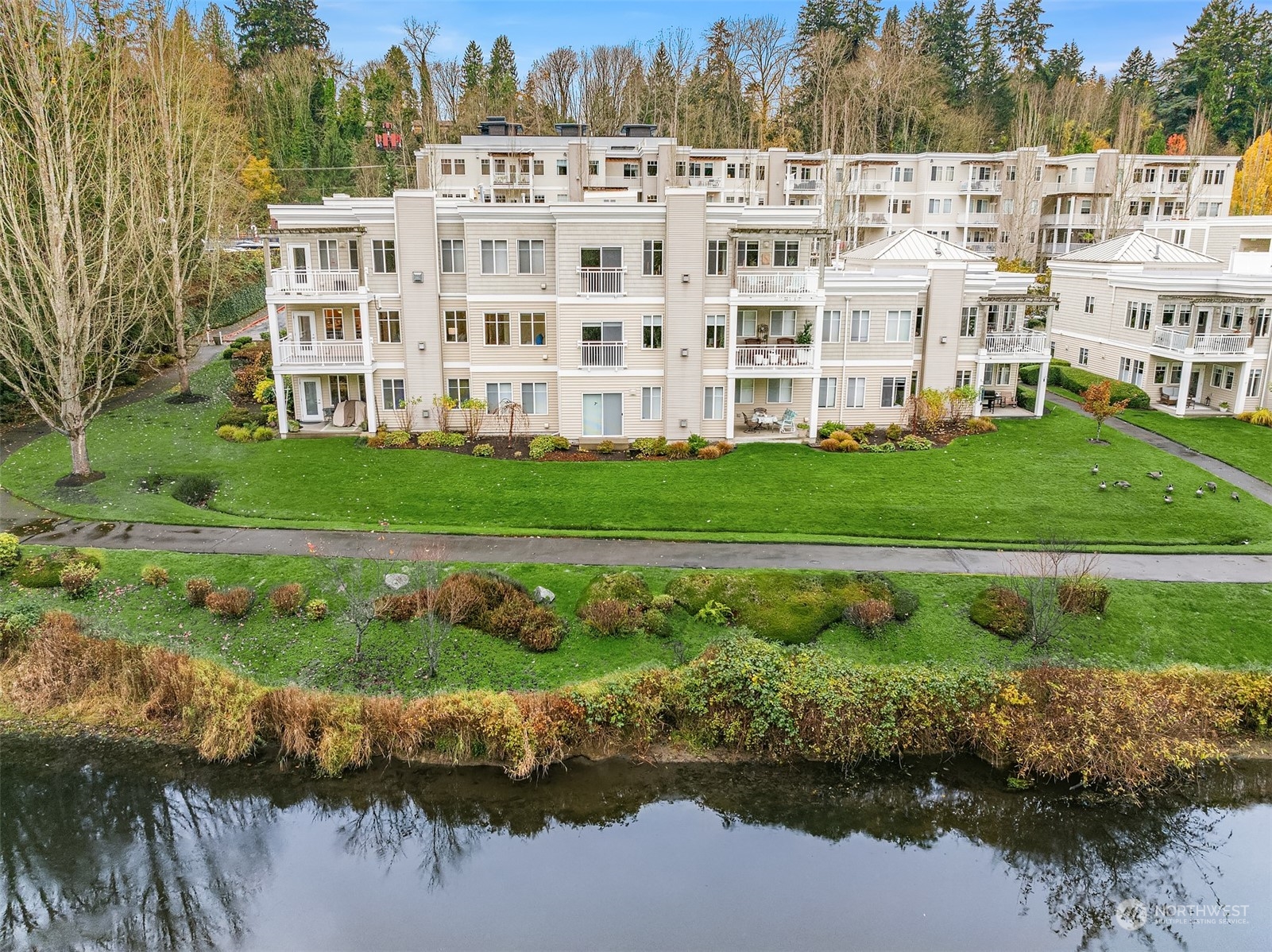 17432 Bothell Way Northeast, Unit B206 Bothell, WA 98011 - Photo 24 of 28 a view of a large white building and a yard with plants and large trees