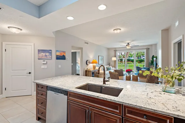 a kitchen with stainless steel appliances kitchen island granite countertop a sink and a refrigerator