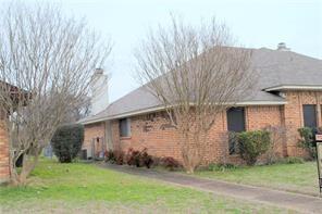 View of property exterior featuring a lawn and brick siding