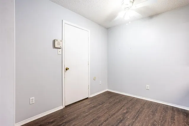 an empty room with chandelier fan and windows