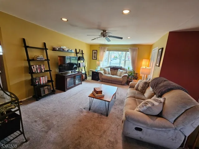 a living room with furniture a flat screen tv and a large window