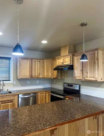 a kitchen with stainless steel appliances granite countertop a sink a stove and a wooden floors