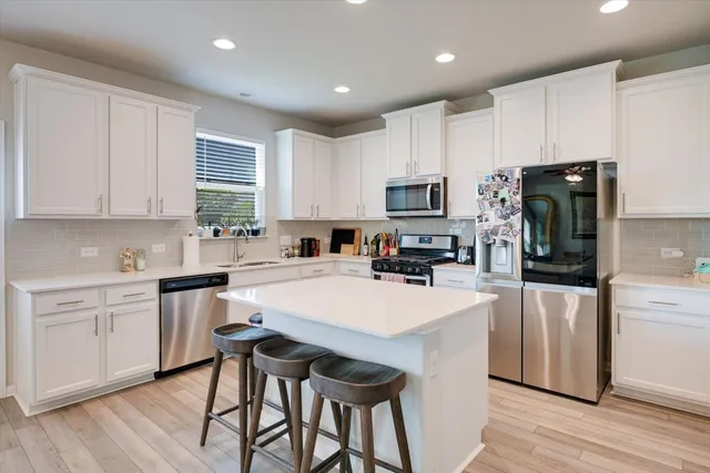 a kitchen with kitchen island a refrigerator stove microwave and cabinets
