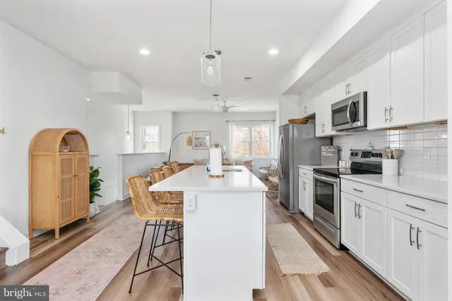 a living room with kitchen island stainless steel appliances furniture a rug and a kitchen view