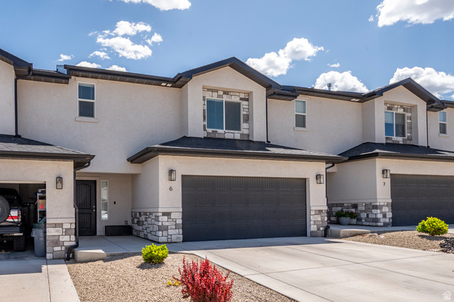 668 East Fiddlers Canyon Road, Unit 6 Cedar City, UT 84721 - Photo 2 of 36 Contemporary townhome exterior featuring light-colored stucco, dark-framed windows, and stone veneer accents