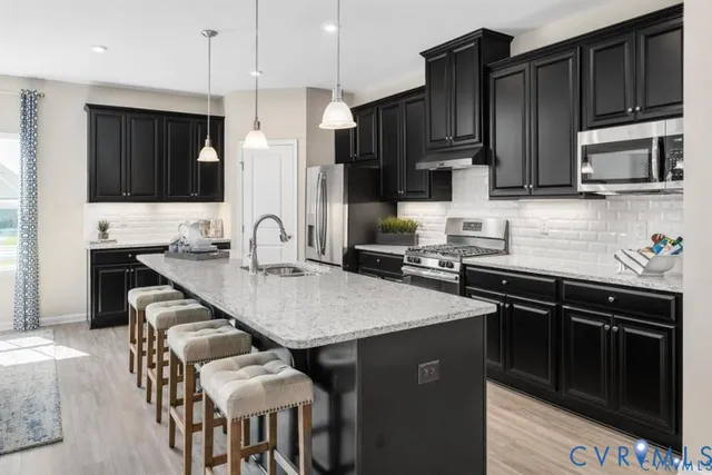 a kitchen with stainless steel appliances wooden cabinets a stove a sink and a microwave