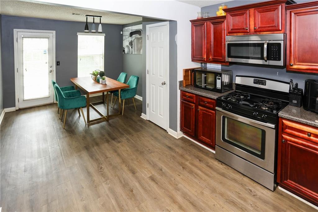 5854 El Segundo Way Atlanta, GA 30349 - Photo 8 of 63 a kitchen with stainless steel appliances a stove a sink dishwasher a microwave oven and a dining table with wooden floor