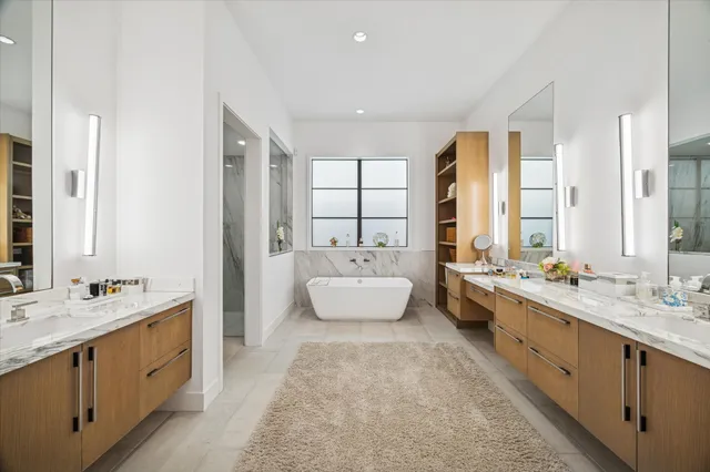 a spacious bathroom with a double vanity sink large mirror and a bathtub