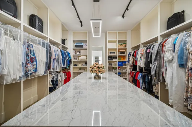 a view of walk in closet with clothes and shoes