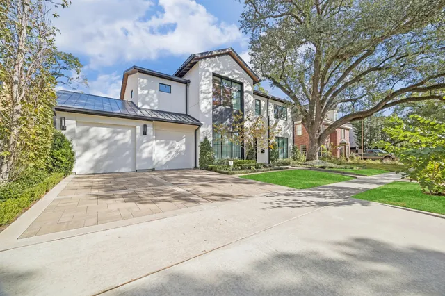 a front view of a house with garden and trees