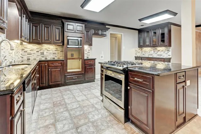 a kitchen with stainless steel appliances granite countertop a stove a sink and a microwave